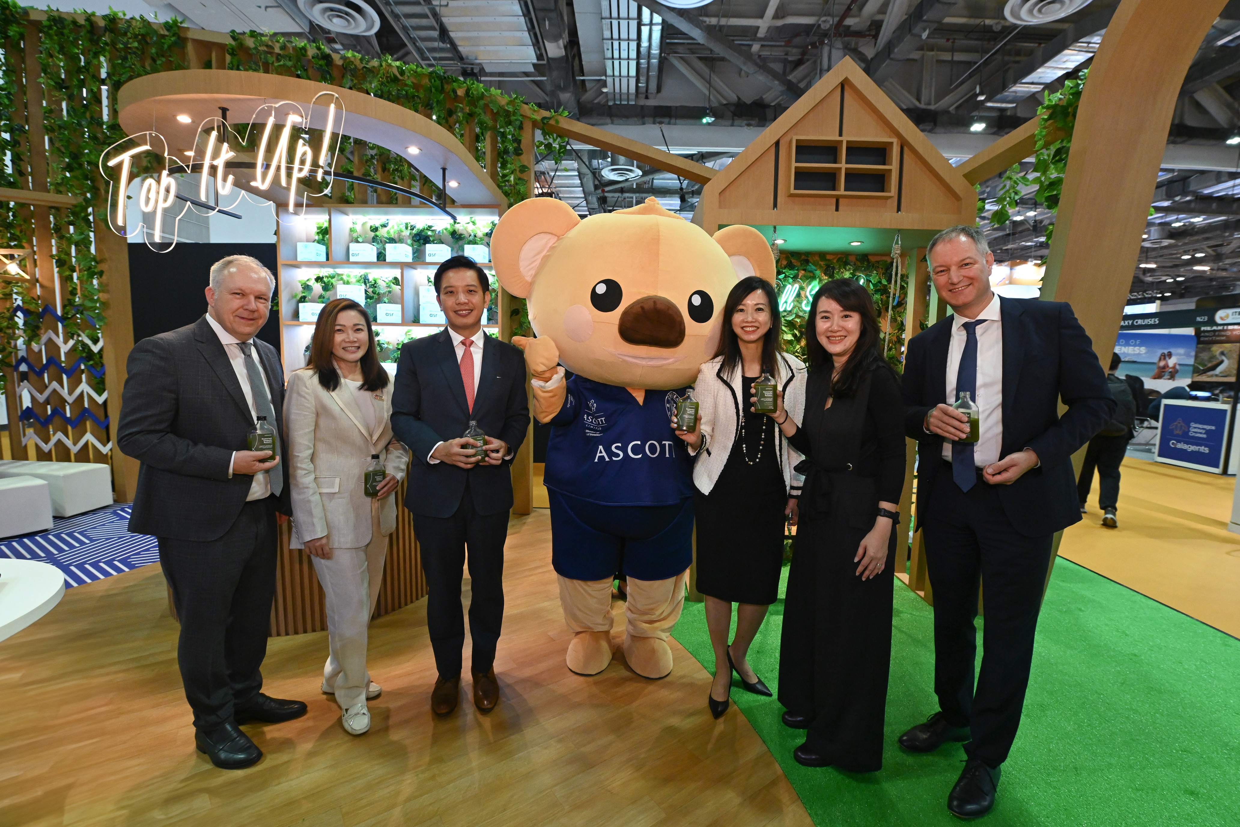 Mr Alvin Tan, Minister of State, Ministry of Trade and Industry and Ministry of Culture, Community and Youth (third from left), enjoying a bottle of healthy green juice crafted to represent the Somerset brand at Ascott’s booth at ITB Asia 2024. He was accompanied by (from left to right) Mr David Ruetz, Senior VP, Messe Berlin; Ms Melissa Ow, Chief Executive, Singapore Statutory Board; Ms Beh Siew Kim, Chief Financial & Sustainability Officer for CLI Lodging and MD of Japan and Korea, Ascott; Ms Tan Bee Leng, Chief Commercial Officer for Ascott; and Mr Mario Tobias, CEO of Messe Berlin, with a special appearance by Cubby, Ascott’s beloved mascot.